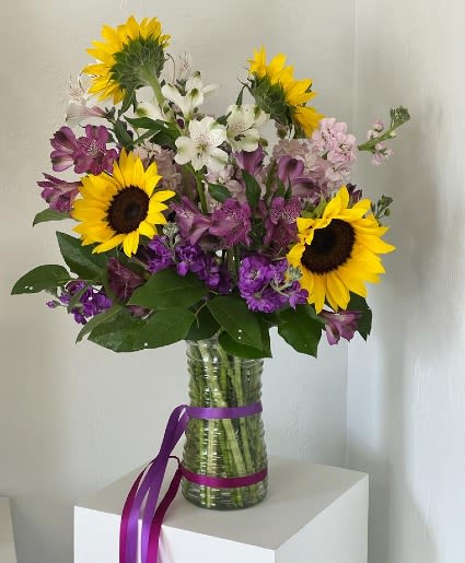 Bouquet of sunflowers, purple and white flowers in a glass vase