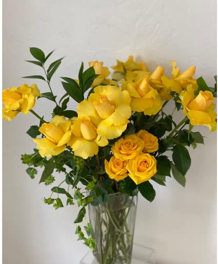 Yellow roses and yellow blooms in a clear glass vase