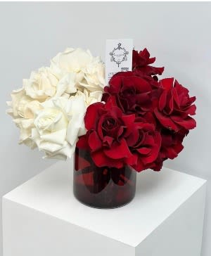 Red and white rose arrangement in a dark glass vase