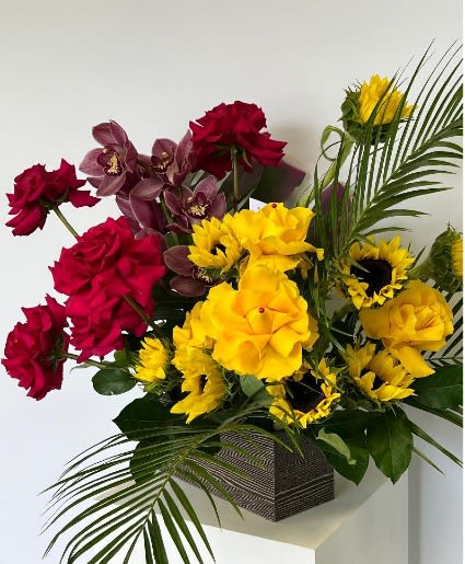 Red and yellow floral arrangement in a square vase