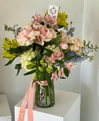 Pink and yellow mixed bouquet in a glass vase with a pink ribbon