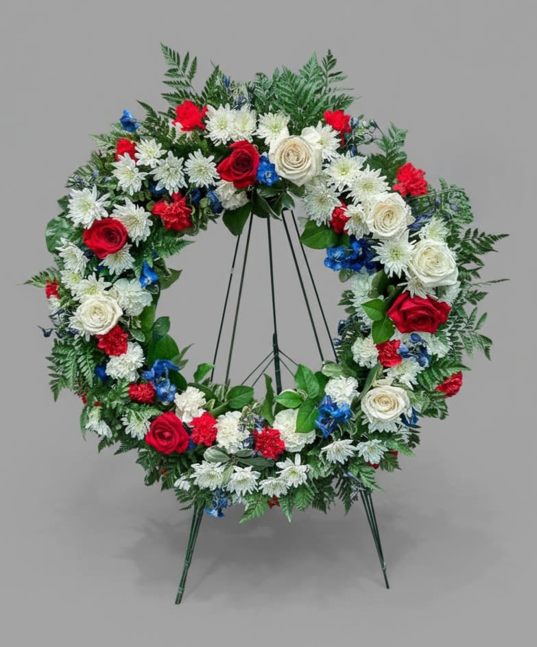 Circular floral wreath on a stand with red, white, and blue flowers