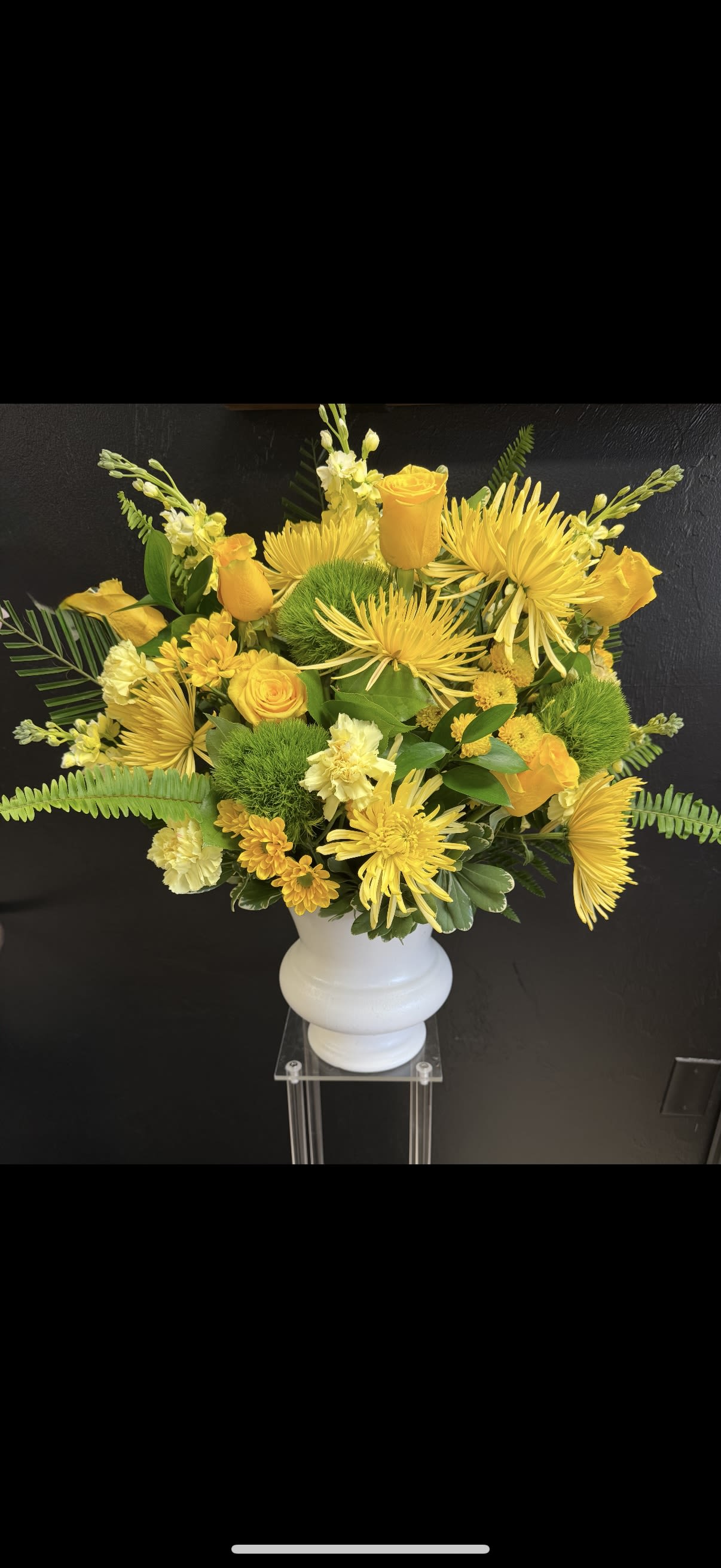 Yellow floral arrangement in a white vase with roses and spider mums