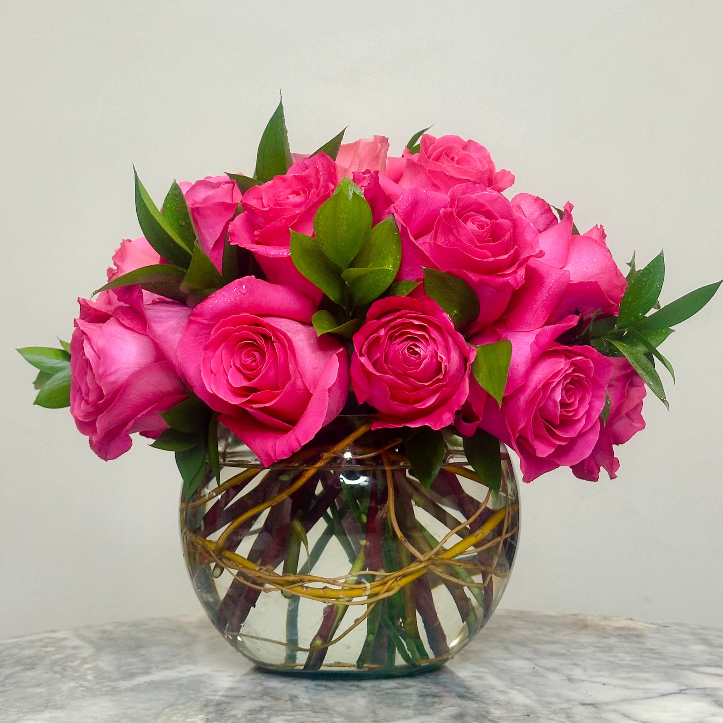 Pink roses arranged in a clear glass bowl vase