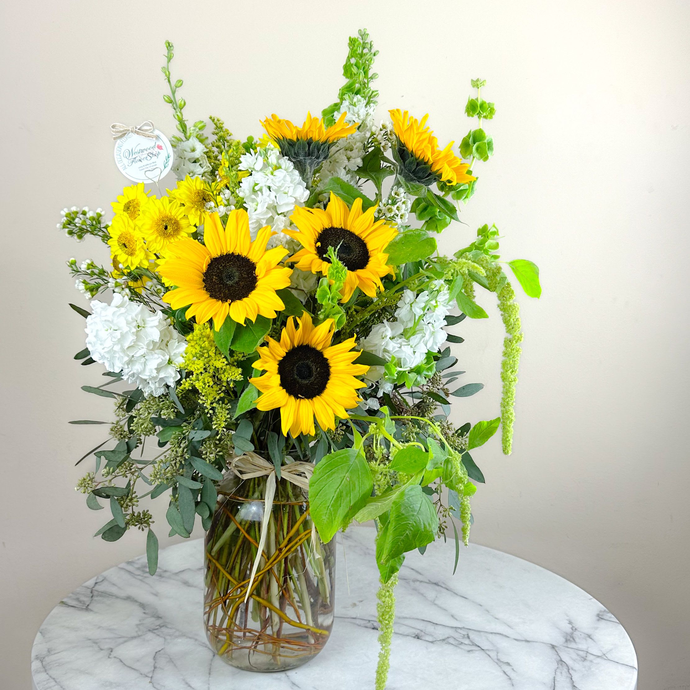 Sunflower arrangement in a glass vase with white blooms and green accents