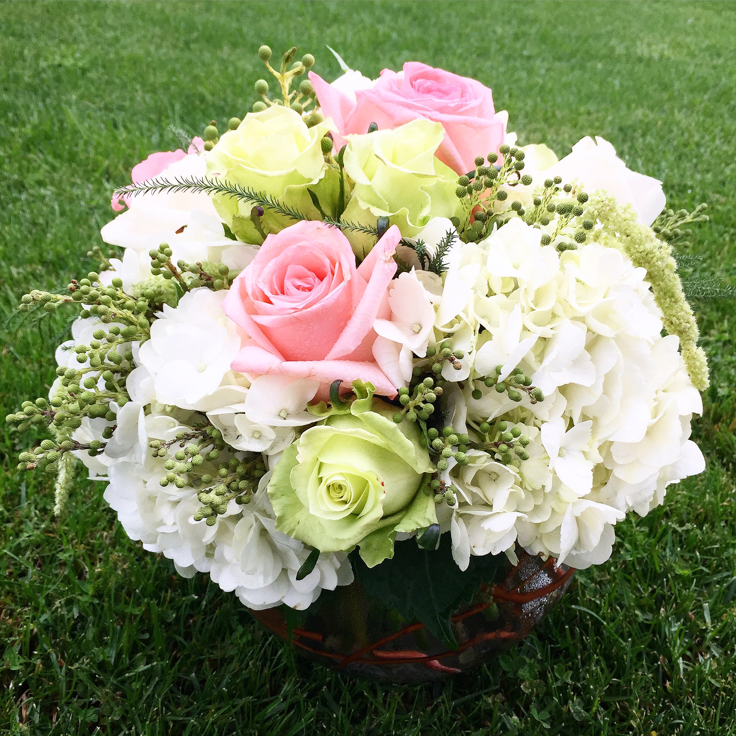 Pink and green roses with white hydrangeas in a basket