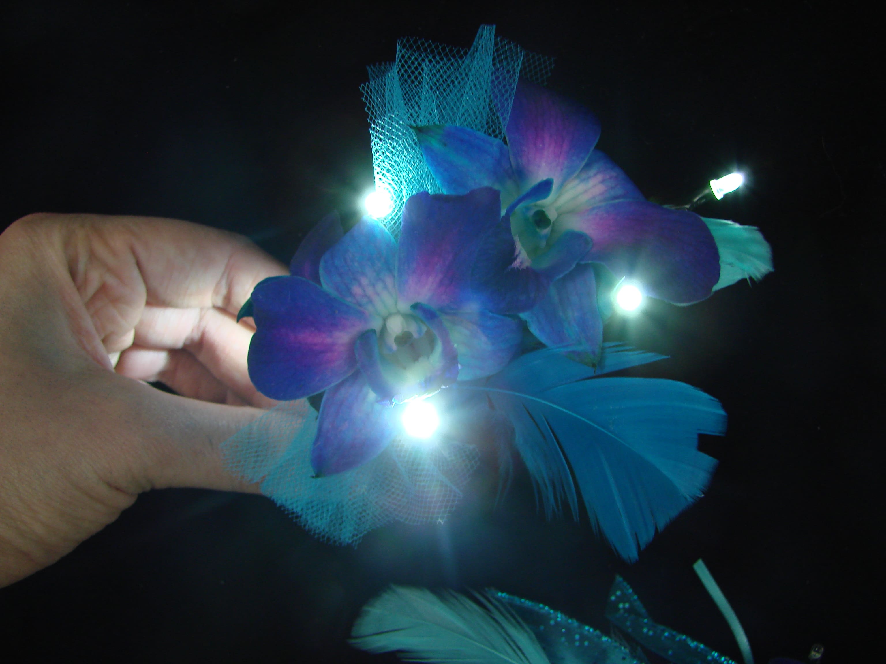 Blue-purple orchid corsage with small lights and feathers