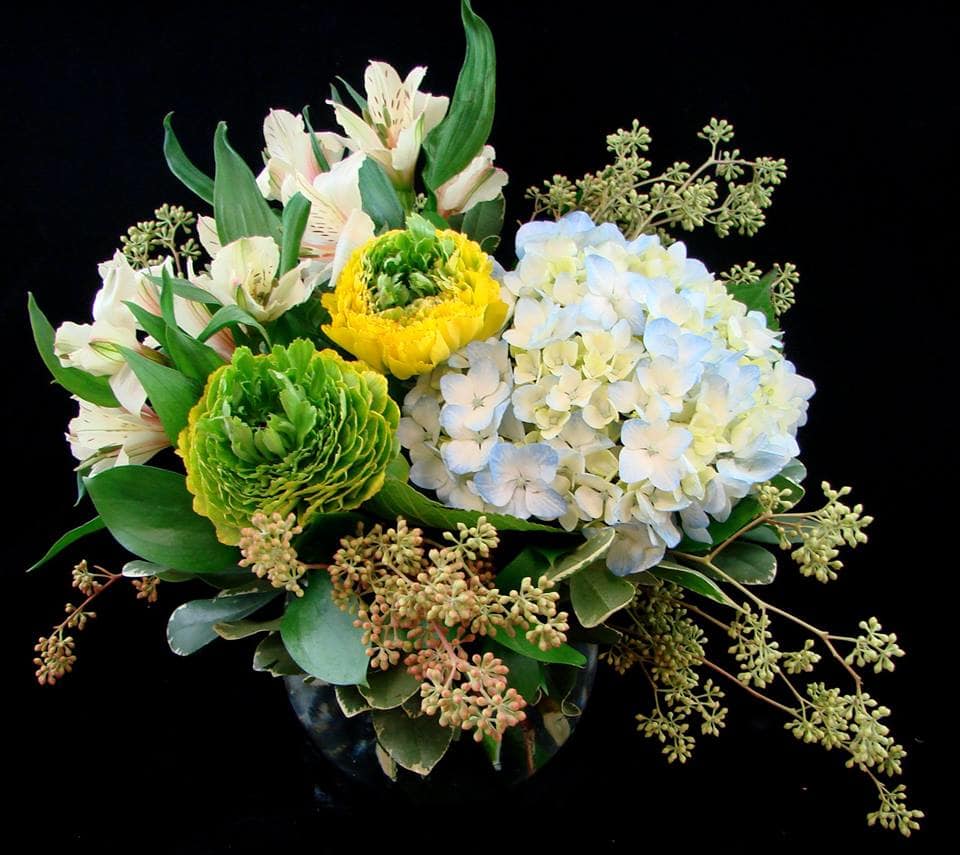 Bouquet of white alstroemeria, green and yellow blooms, and pale blue hydrangea in a vase