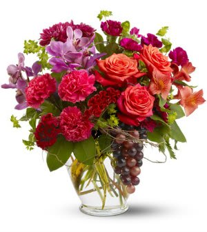 Mixed bouquet of roses, carnations, orchids, and lilies in a glass vase