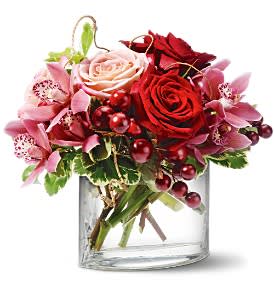 Bouquet of red and pink roses with orchids in a clear glass vase