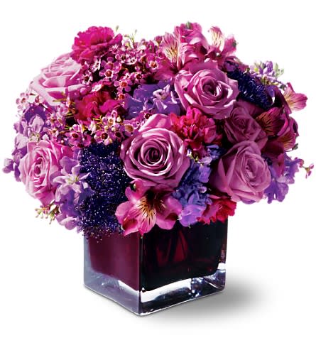 Purple and pink rose bouquet in a square glass vase
