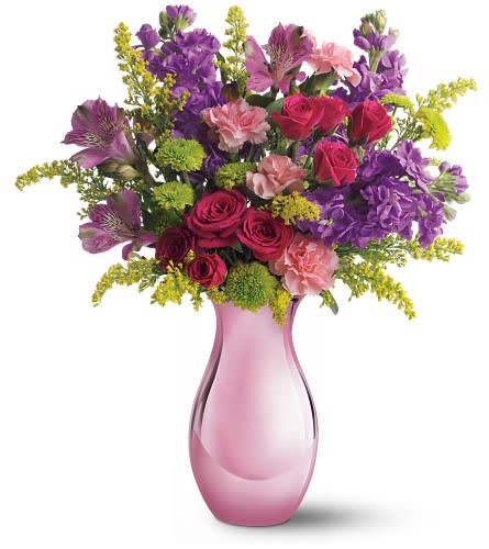 Pink vase holding a mixed bouquet of roses, purple blooms, and carnations