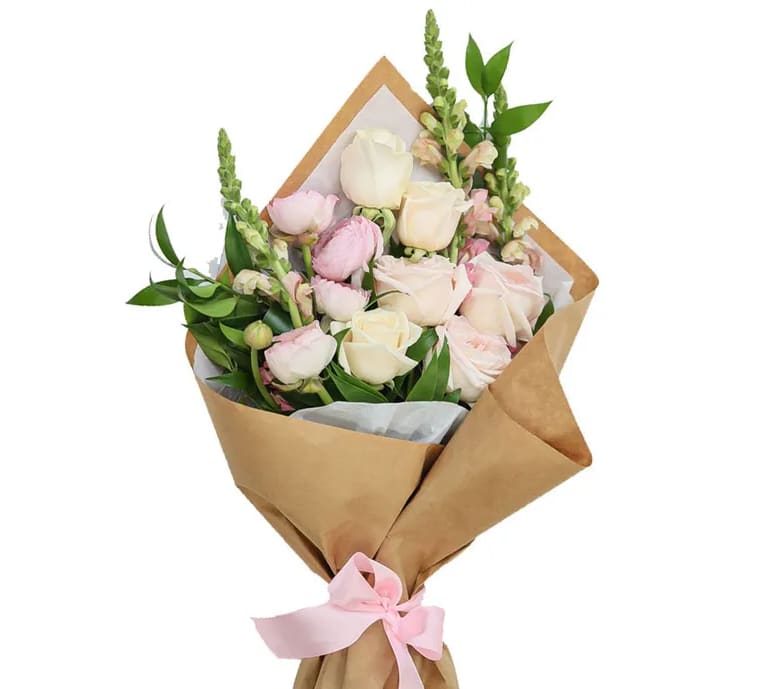 Bouquet of pale pink and white roses wrapped in brown paper with a pink ribbon