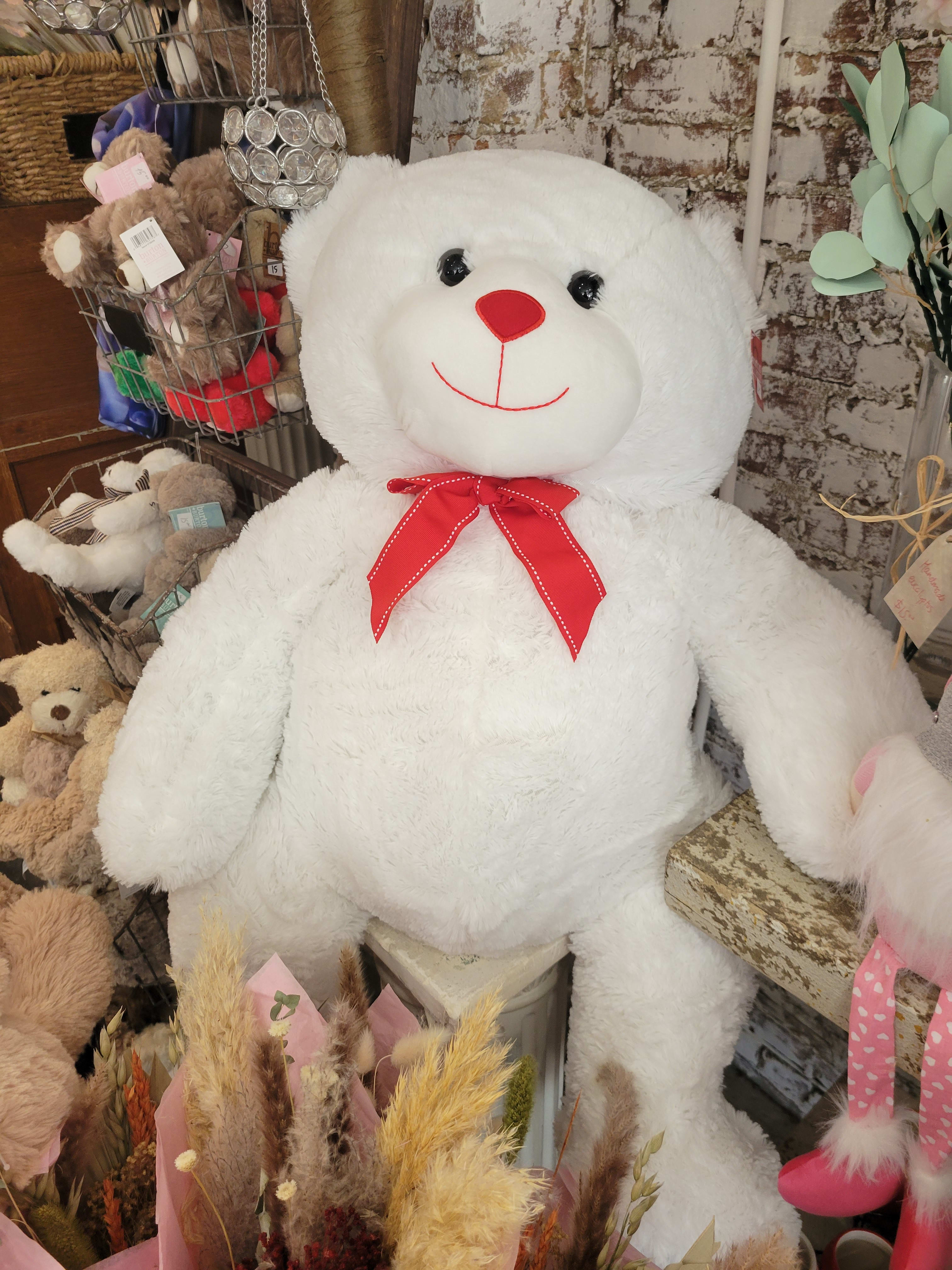 Large white teddy bear with a red bow tie