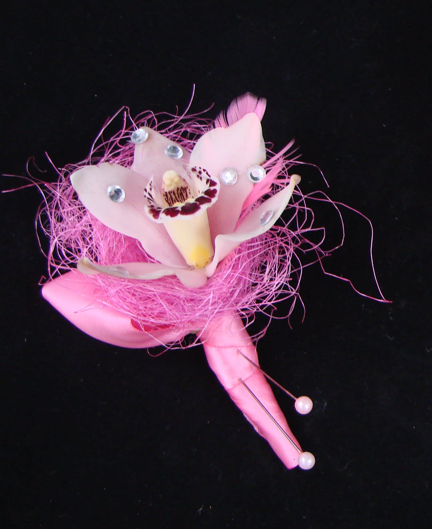 Pink orchid corsage with rhinestone accents on a black background