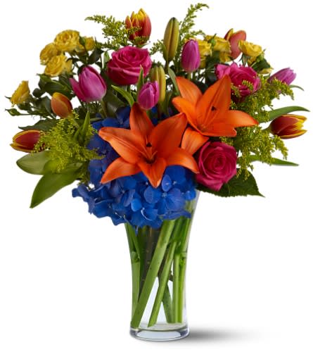 Colorful bouquet of lilies, roses, tulips, and hydrangeas in a glass vase