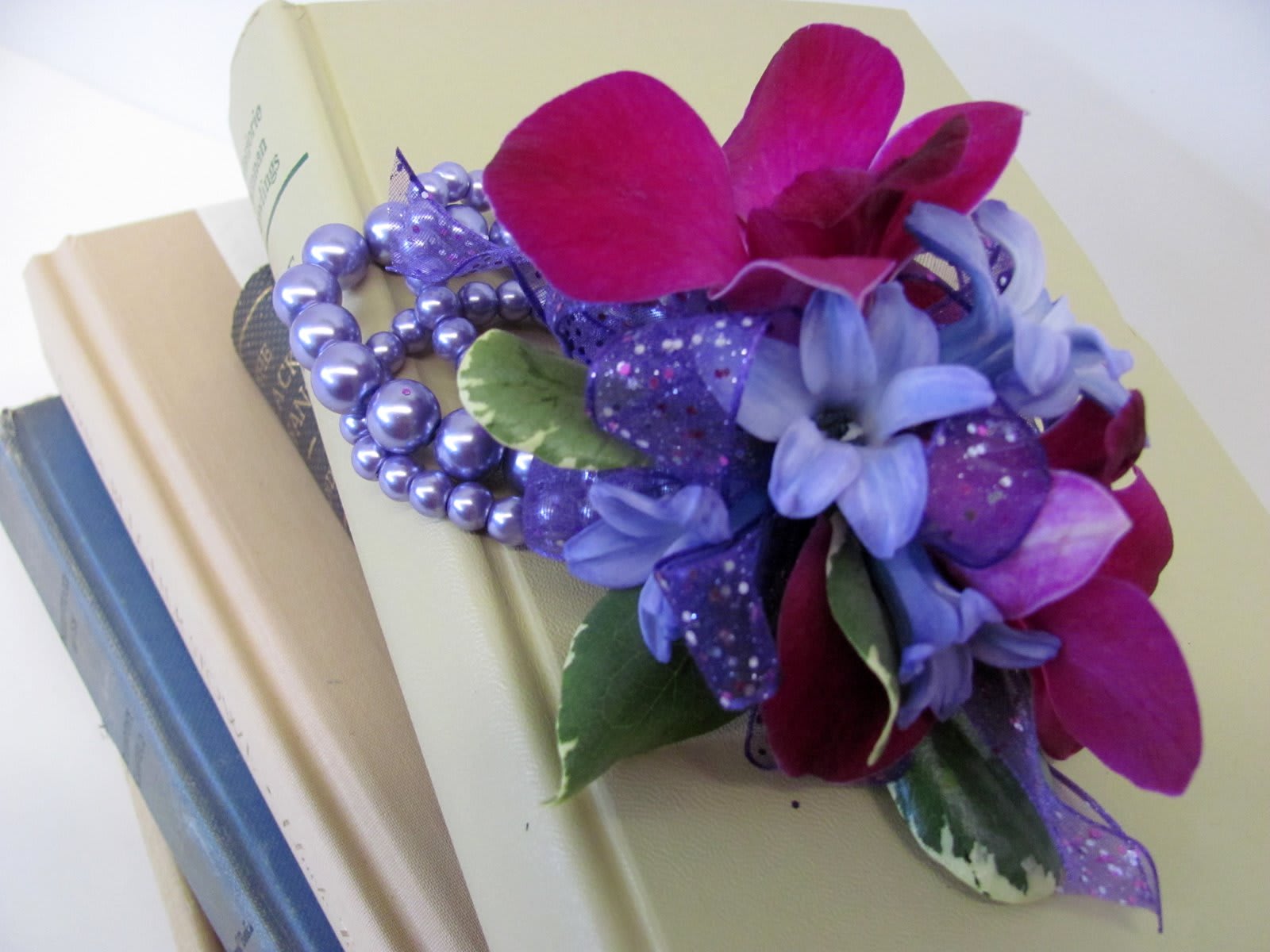 Purple floral corsage with beads on a book stack