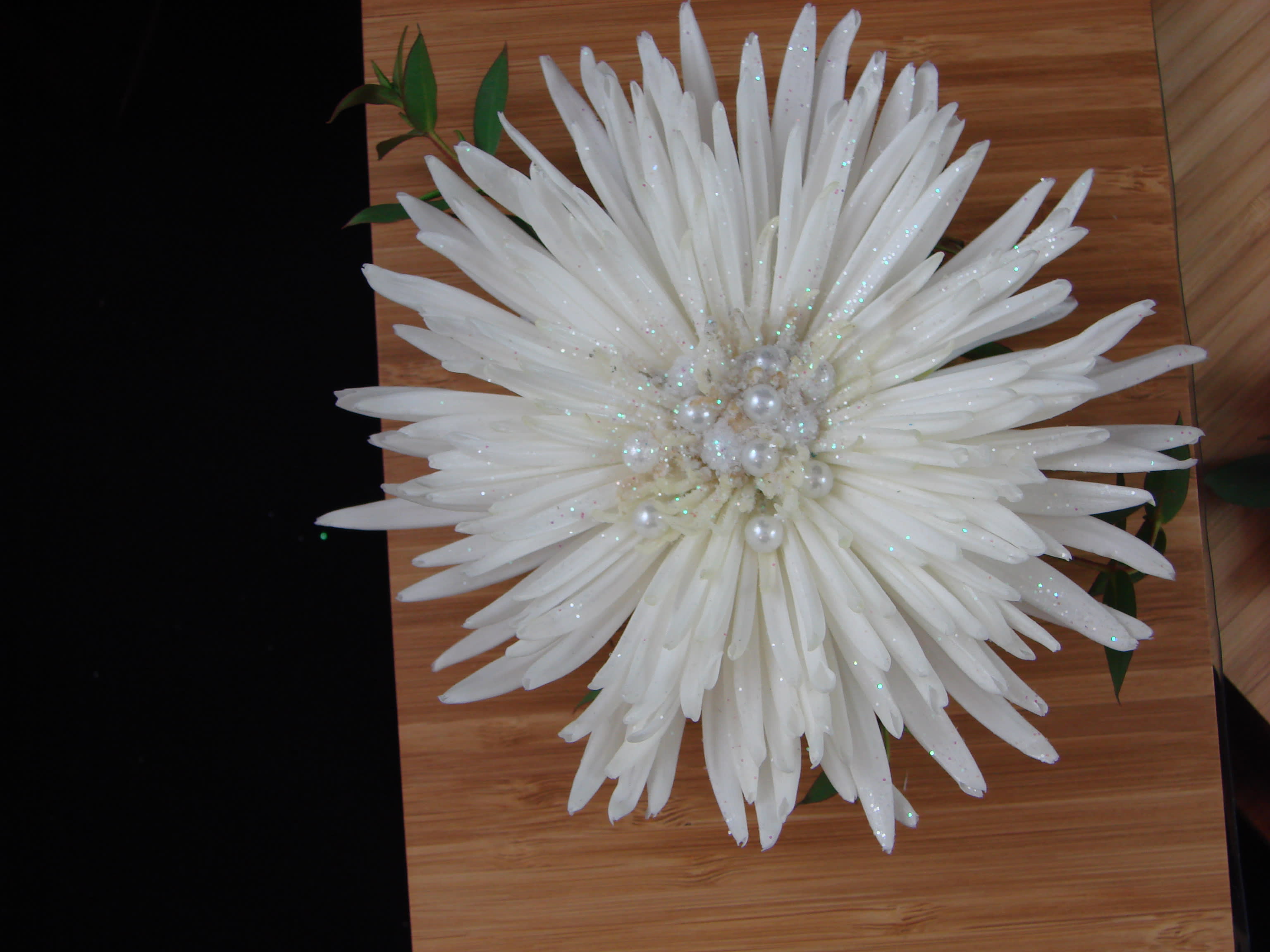 Large white flower with pearl center on a wooden surface