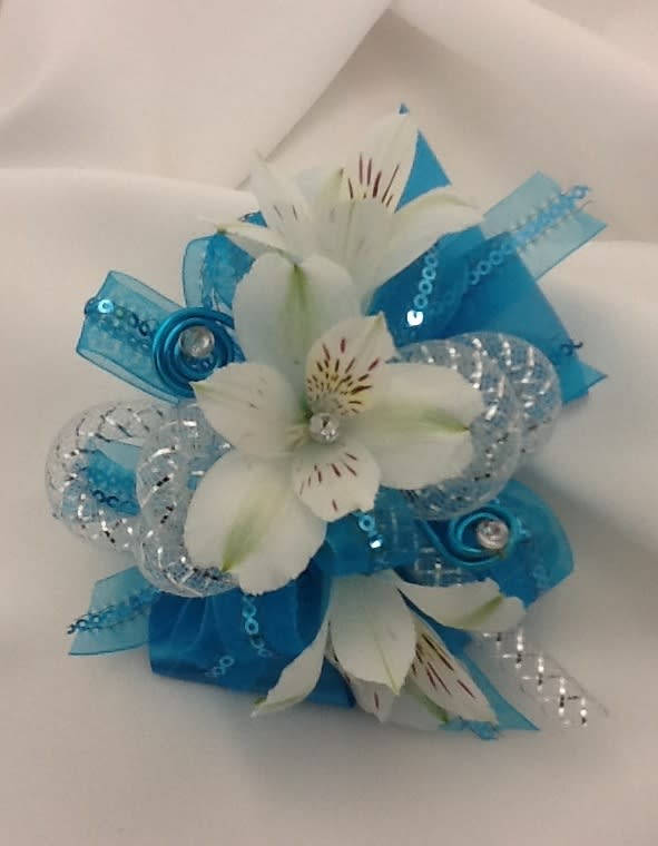 White flowers with blue ribbon and silver accents arranged in a small bouquet