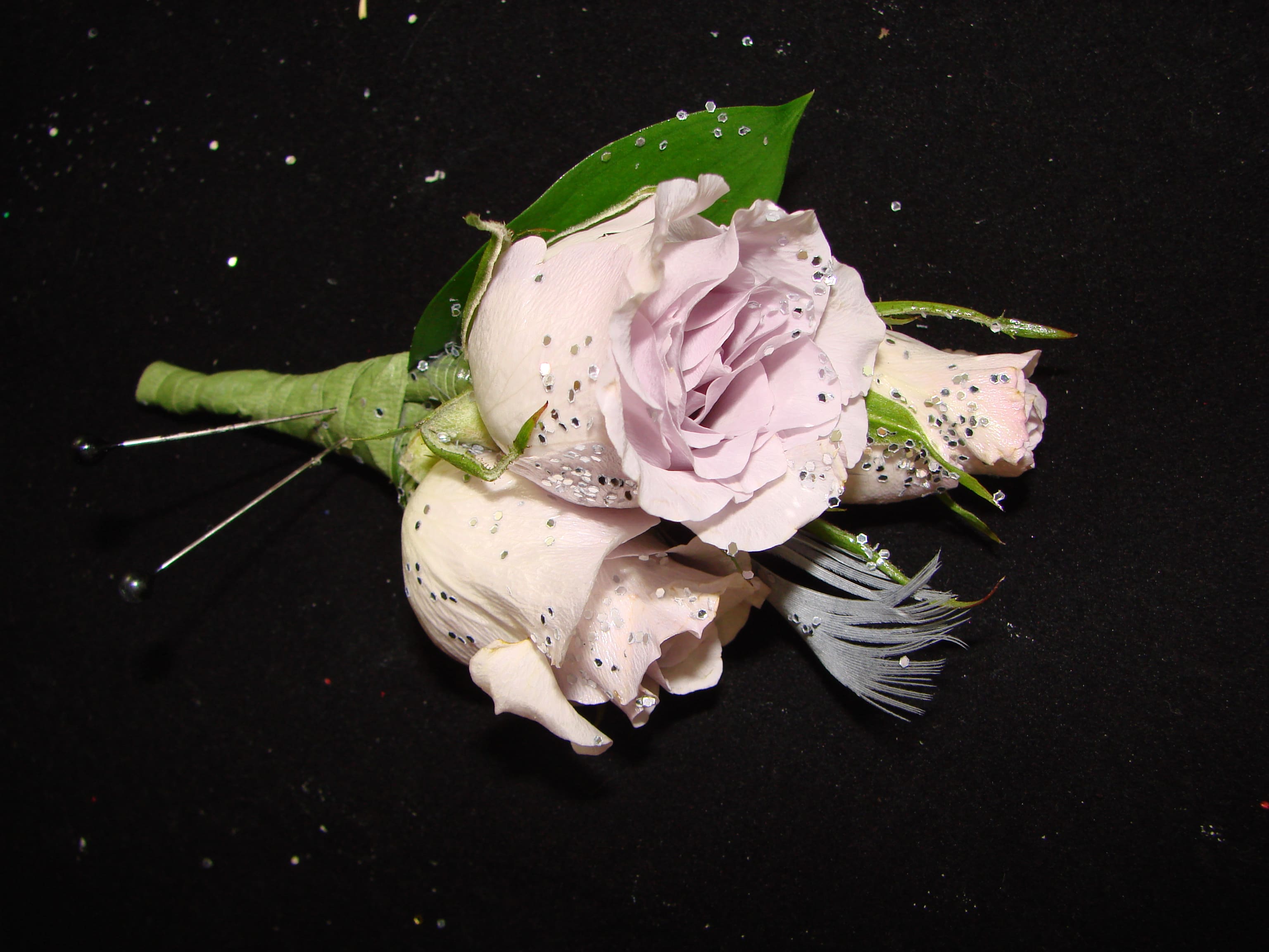 Small pale pink rose boutonniere with a feather accent