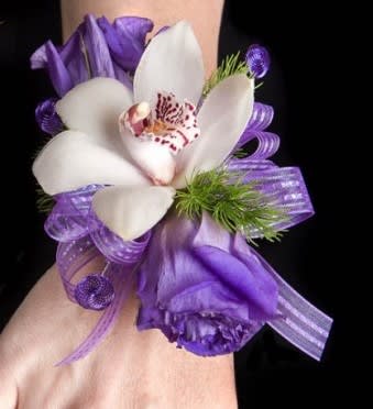 Purple and white orchid corsage with ribbon on a wrist