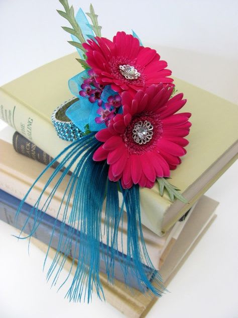 Two pink gerbera daisies on stacked books with blue ribbon accents