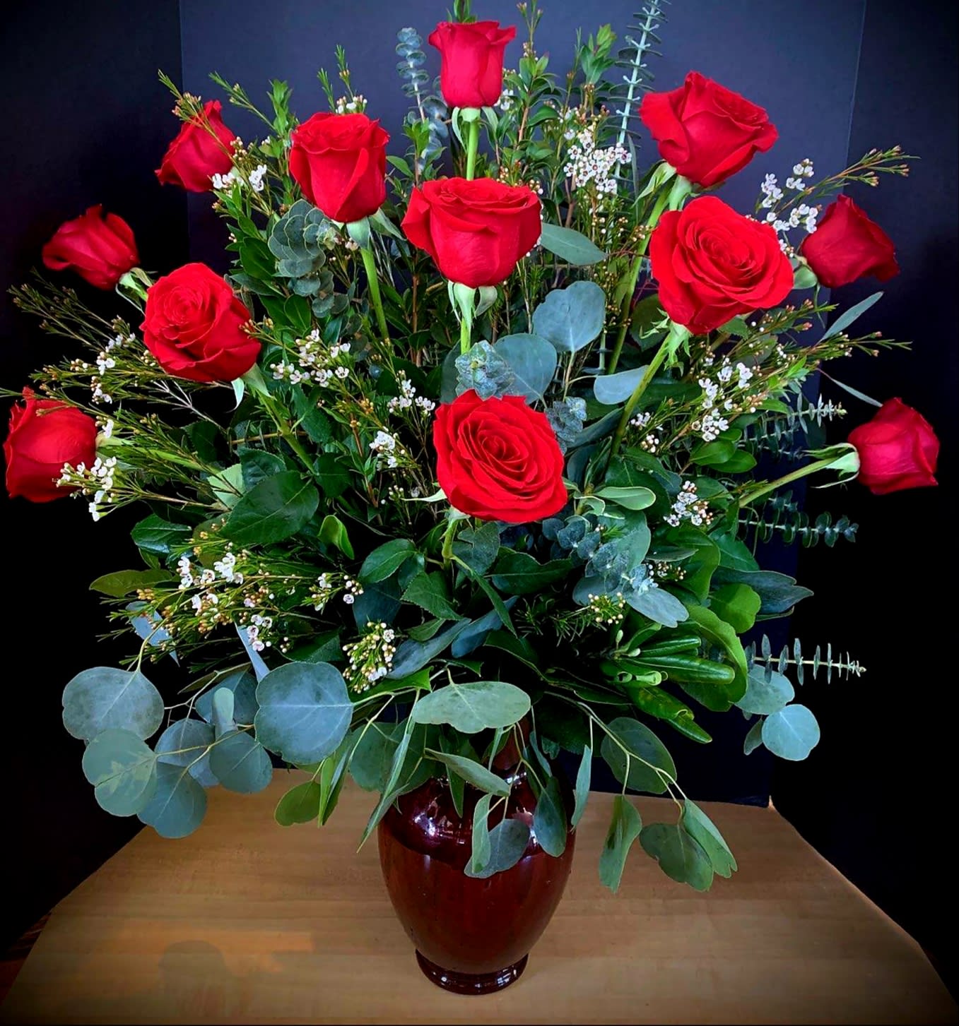 Tall bouquet of red roses in a dark vase