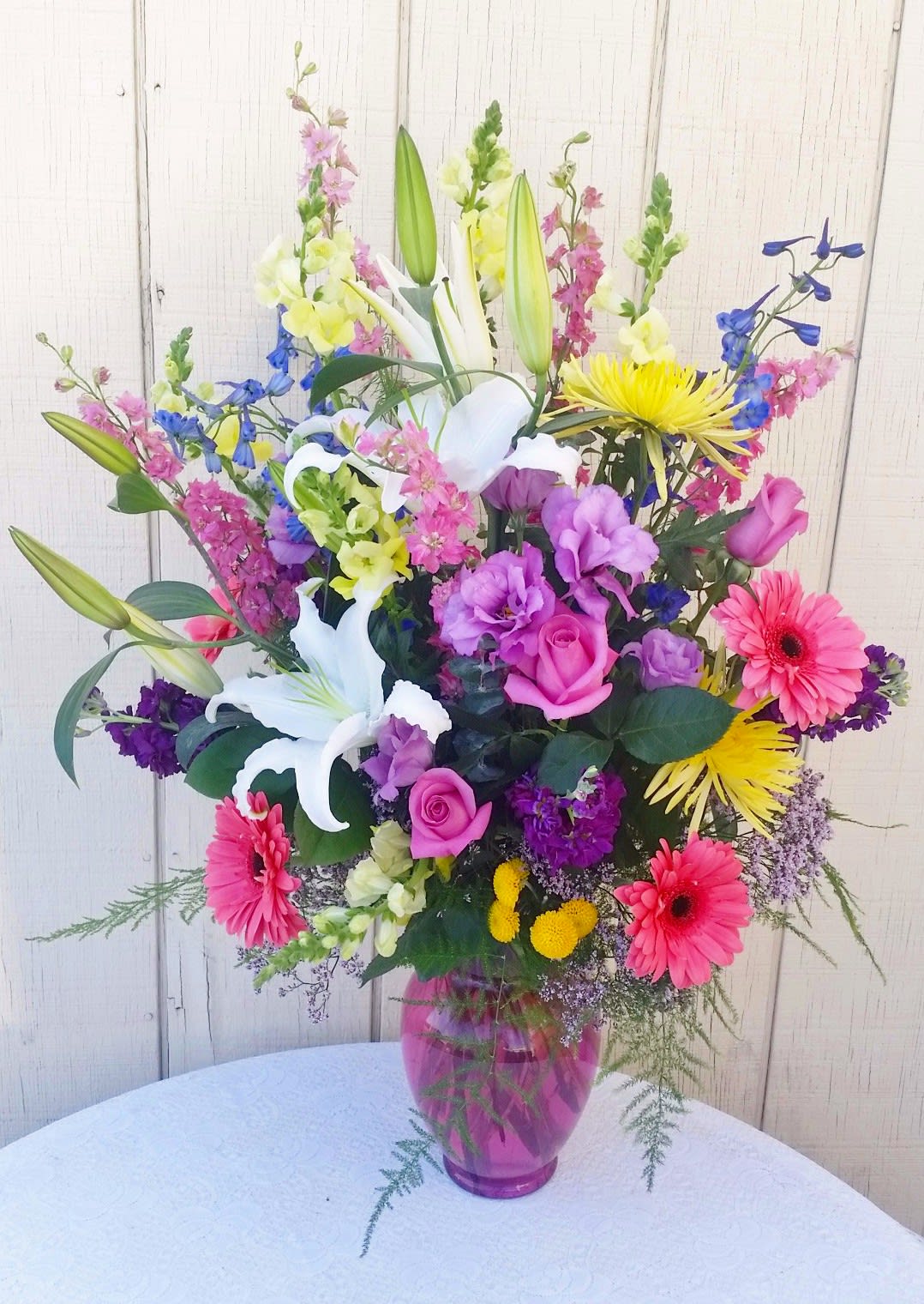 Endless Love bouquet - Beautiful blend of Gerberas, Lilies, Roses, Lisianthus, Delphinium, larkspur, snapdragons and chrysanthemums arranged in a pink glass vase. This arrangement is 24"h X 18-20"w. 
