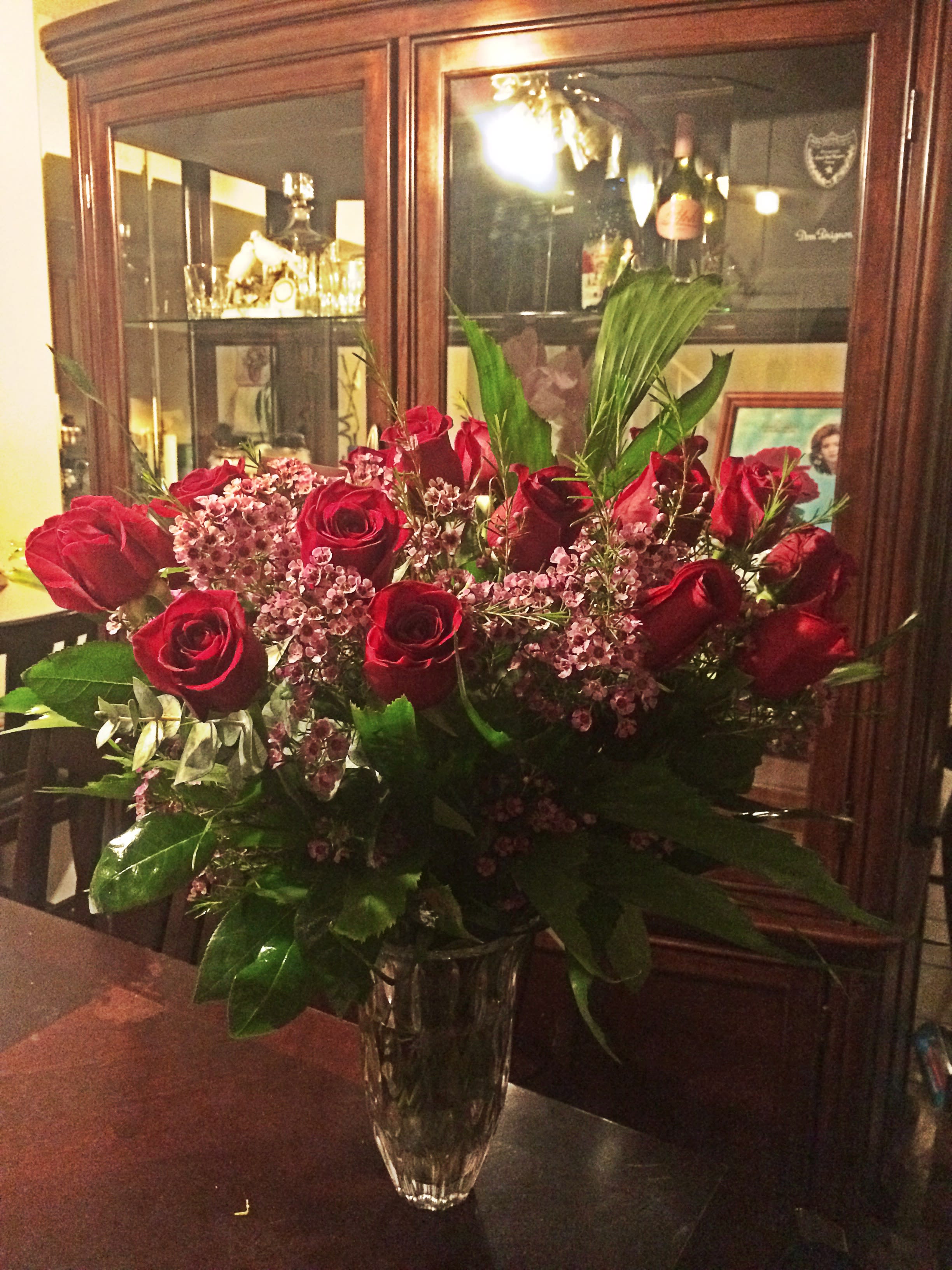 Red roses and pink filler flowers in a clear glass vase