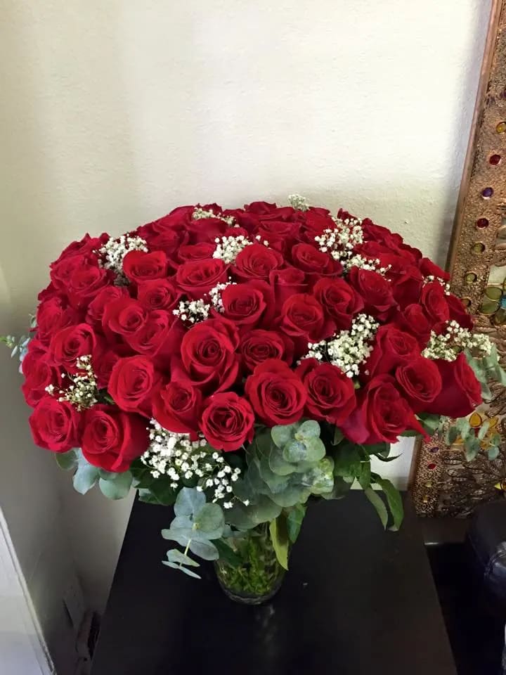 Large bouquet of red roses in a glass vase with white filler flowers