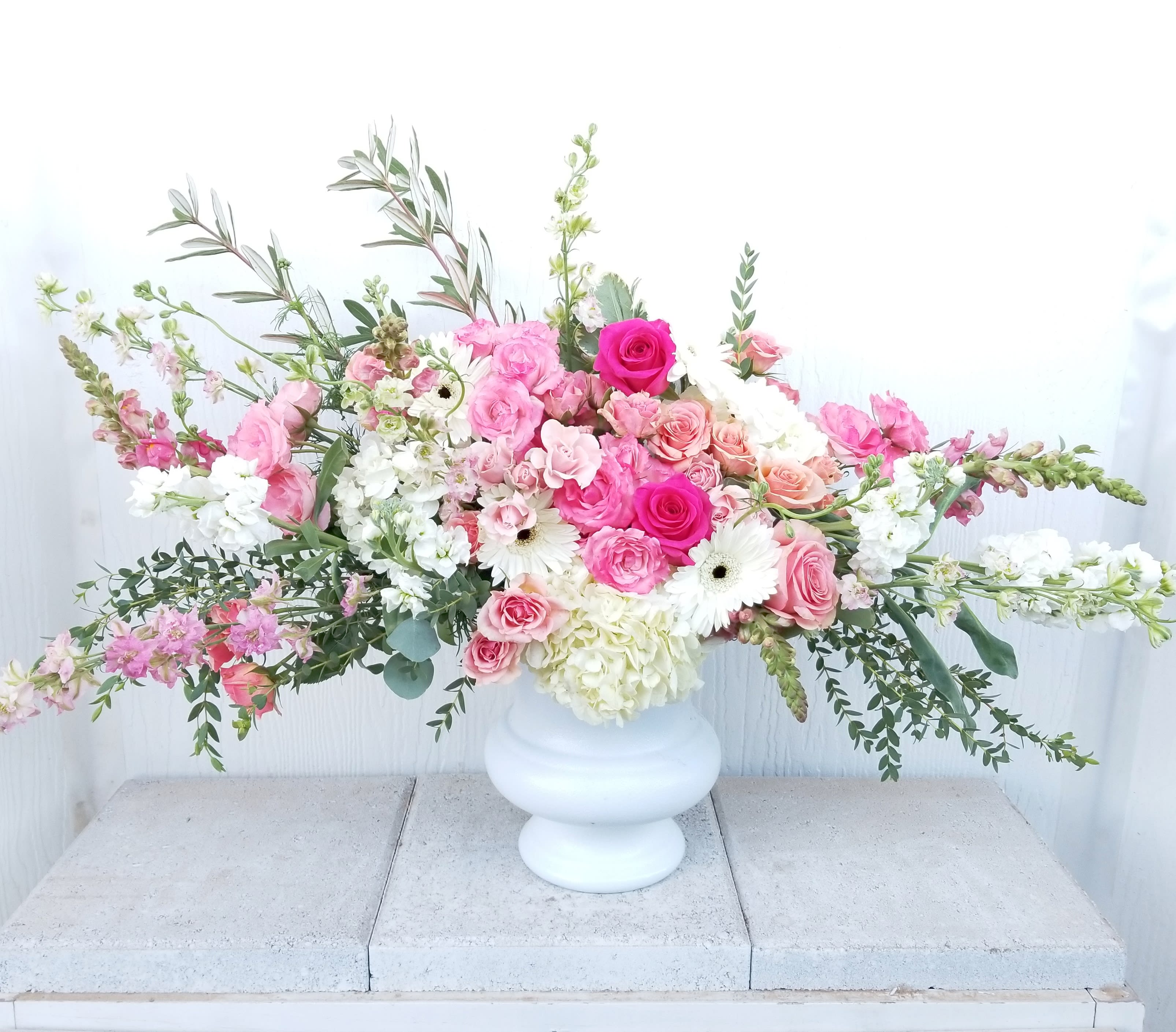 Large pink and white floral arrangement in a white vase