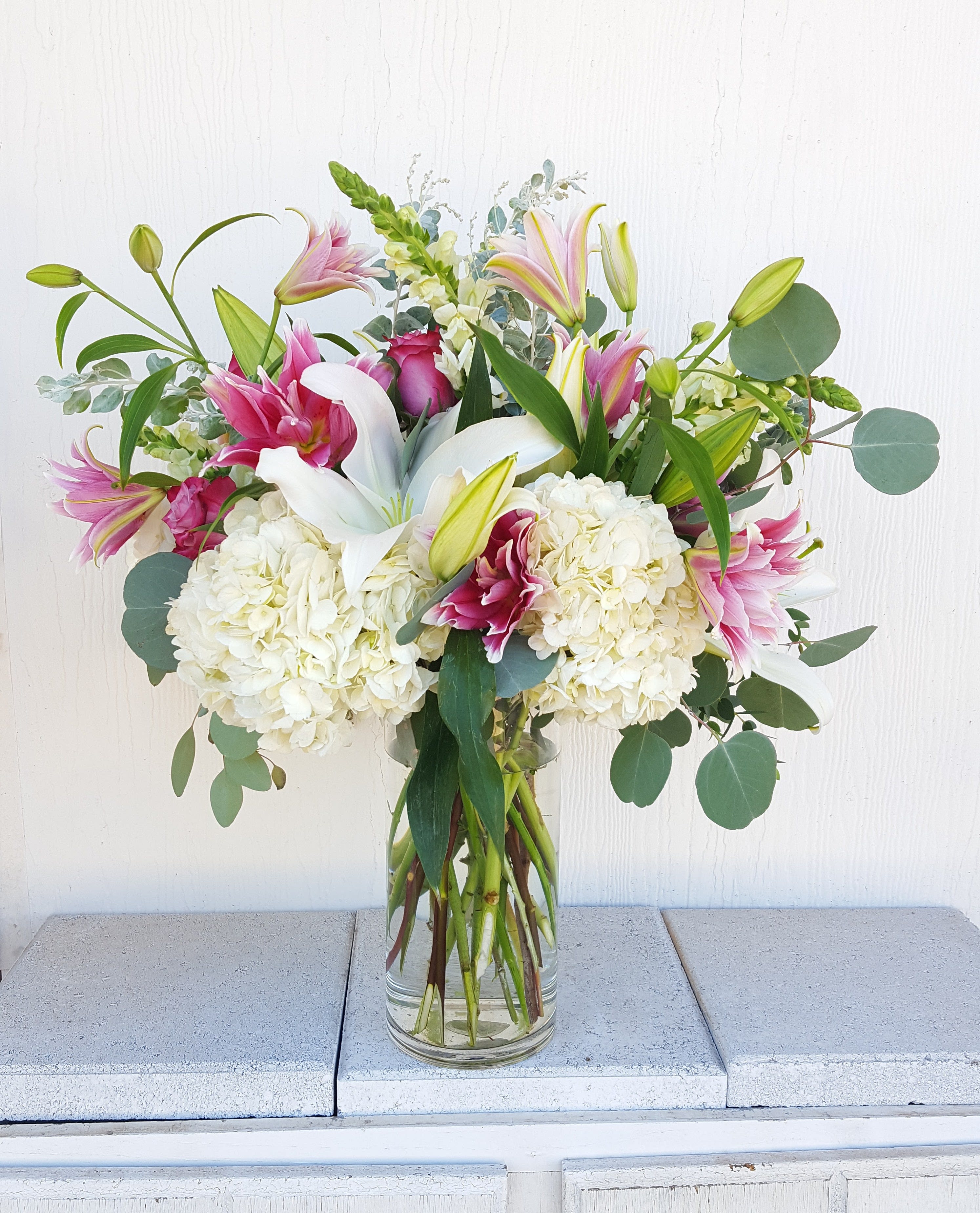 Bouquet of pink lilies, white hydrangeas, and eucalyptus in a glass vase