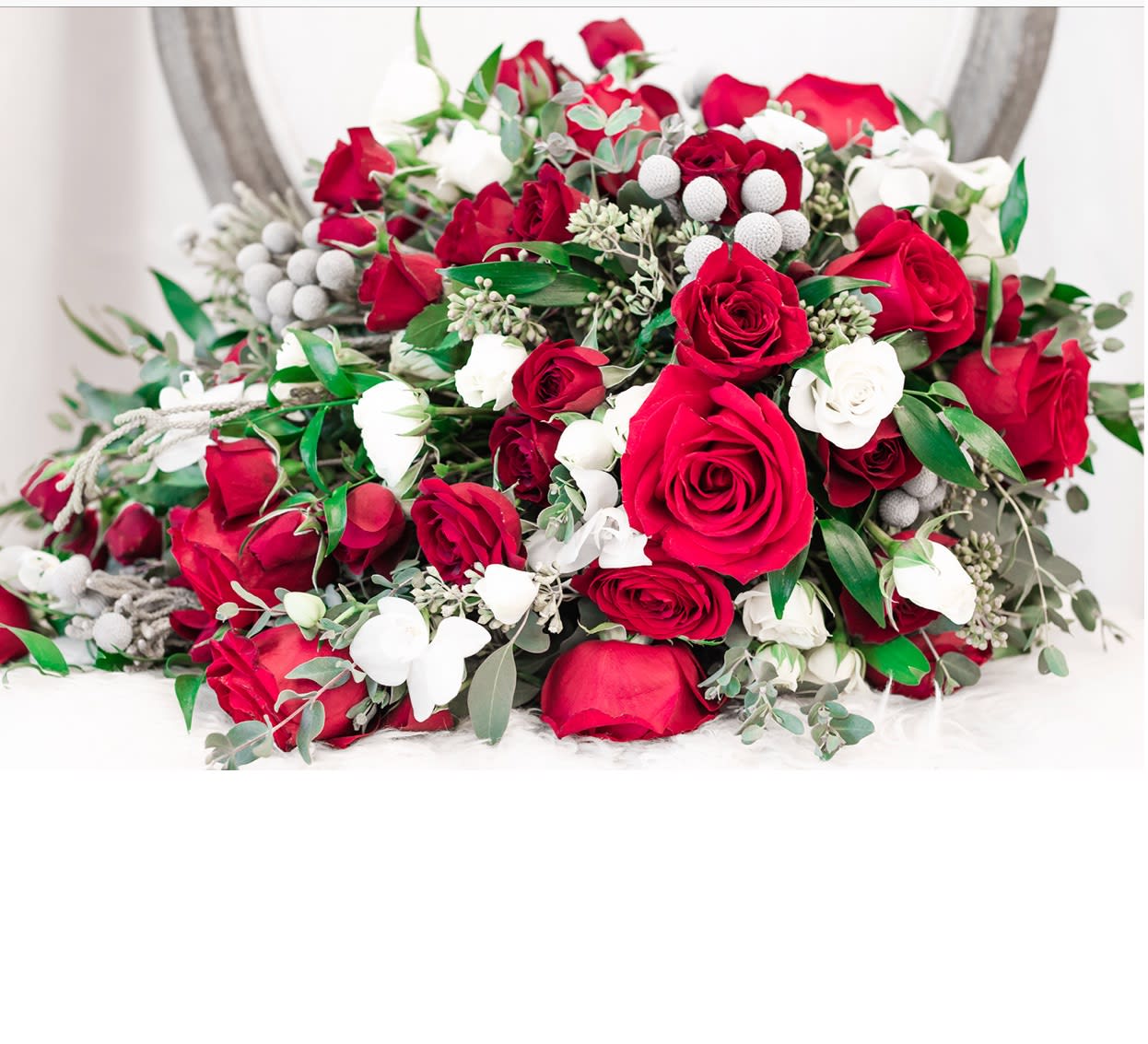 Bouquet of red and white roses with greenery and white berry accents