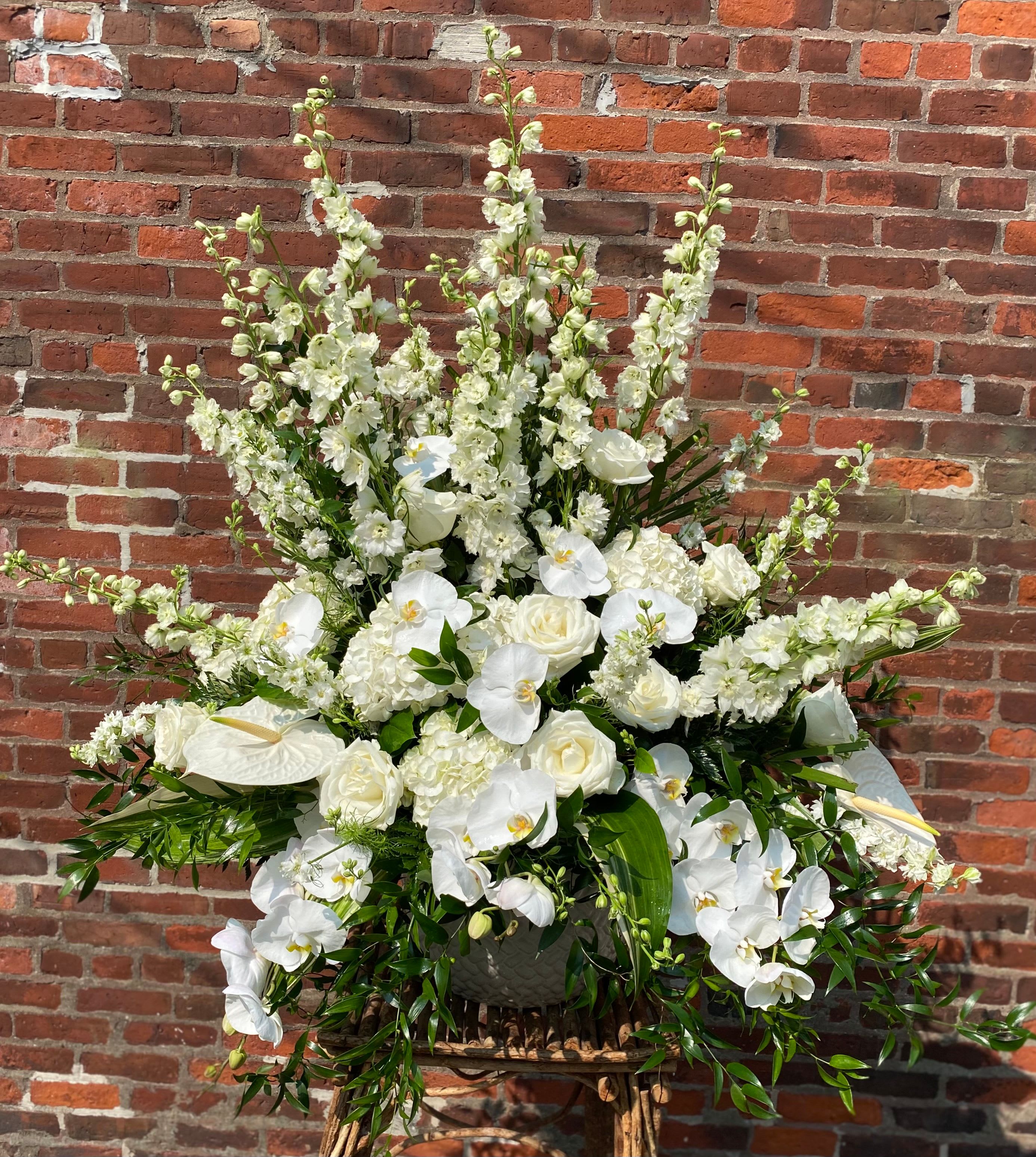 Large white floral arrangement with orchids and roses in a basket