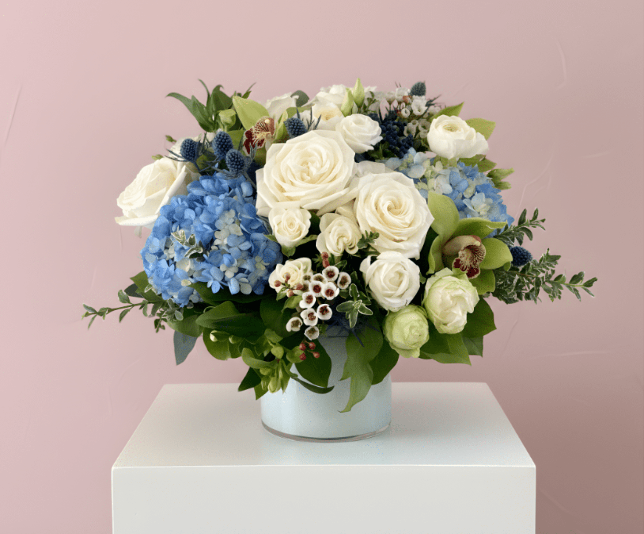 White roses and blue hydrangeas arranged in a white vase