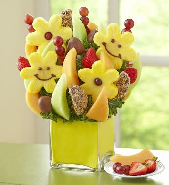 Smiles All Around - Product ID: 102423   Joy is all around with this smile-filled Fruit Bouquet in a chic cube vase. Itâs the perfect way to brighten birthdays, anniversaries, or any day at all. Juicy strawberries, honeydew melon and cantaloupe wedges, pineapples daisies with grape centers, pineapple daisies dipped and decorated with a smiley face, dipped strawberries, dipped apple wedges, grape skewers and more Arrives in a stylish, reusable glass cube vase with a yellow foam insert; measures 5"H x 5"D Hand-crafted and designed by local shops Delivered fresh to their door with Same-Day Delivery