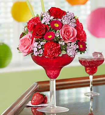 Strawberry Floral Margarita - Product ID: 91076  EXCLUSIVE Fresh, fun, and fabulous all over, this stylishly sweet, hand-crafted arrangement of roses, asters, carnations and dianthus gets the party started with a touch of pink perfection. Designed in an oversized acrylic margarita glass, it's a truly original way to make any hour Happy Hour. Hand-designed fresh floral cocktail of roses, asters, carnations, dianthus and variegated pittosporum Artistically arranged by our select florists in an acrylic margarita glass; measures 10"H Extra Large arrangement measures approximately 14"H x 9"L Large arrangement measures approximately 13"H x 8.5"L Medium arrangement measures approximately 12"H x 8"L Small arrangement does not include dianthus and measures approximately 12"H x 7"L Our florists select the freshest flowers available so colors and varieties may vary