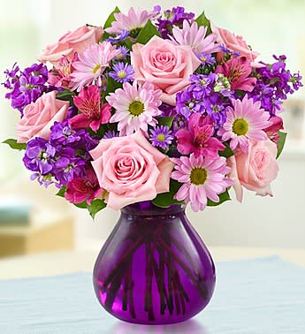 Lavender Dreams - Product ID: 90228  Send her this truly original bouquet of lovely roses, daisy poms, stock, alstroemeria and monte casino in shades of pink and purple. Delivered in a stylish purple glass vase to bring out the richness of color -- and help you express yourself perfectly. Hand-crafted arrangement of roses, daisy poms, alstroemeria, stock, monte casino and salal created in honor of Womenâs Week Artistically designed by our expert florists in a chic purple glass vase; measures 7"H Large arrangement measures approximately 15.5"H x 11"D Medium arrangement measures approximately 15"H x 10.5"D Small arrangement does not include roses and measures approximately 14"H x 10"D Our florists hand-design each arrangement, so colors, varieties, and container may vary due to local availability