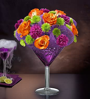 Shocktail Bouquet - Product ID: 91892   EXCLUSIVE Our shocking cocktail-shaped arrangement is shaking things up for Fall! The perfect potion of fresh roses, carnations and poms is served up in an oversized, reusable martini glass to make birthdays and Halloween parties a real scream. Halloween-themed Happy Hour arrangement crafted from roses, carnations and poms Hand-designed by our florists in an oversized acrylic martini glass and finished with purple poly mesh; glass measures 9"H Large arrangement measures approximately 15"H x 10"L Medium arrangement measures approximately 14"H x 9"L Small arrangement measures approximately 12.25"H x 7"L Our florists select the freshest flowers available, so colors, varieties and container may vary due to local availability This gift is available in participating areas only. Enter the recipient's zip code, and select the delivery date for availability.