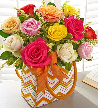 Blooming Roses - Product ID: 140150  For the woman who always inspires you, capture her colorful personality with our vibrant rose arrangement. Blooming in pretty pastel shades and artistically designed with bright solidago in a keepsake tote bag, it's a truly original way to make her day unforgettable. Hand-designed arrangement of our freshest assorted long-stem roses, accented with solidago and variegated pittosporum Arrives in a lined reusable handled canvas tote with orange, white, green and yellow chevron design; measures 8.25"H Stylish tote is perfect to take on the go to the salon, spa, work, or a get-together with friends (see above images for examples of after use) Large arrangement measures approximately 16"H x 13"L Small arrangement measures approximately 15"H x 12"L Our florists select the freshest flowers available, so floral colors and varieties may vary