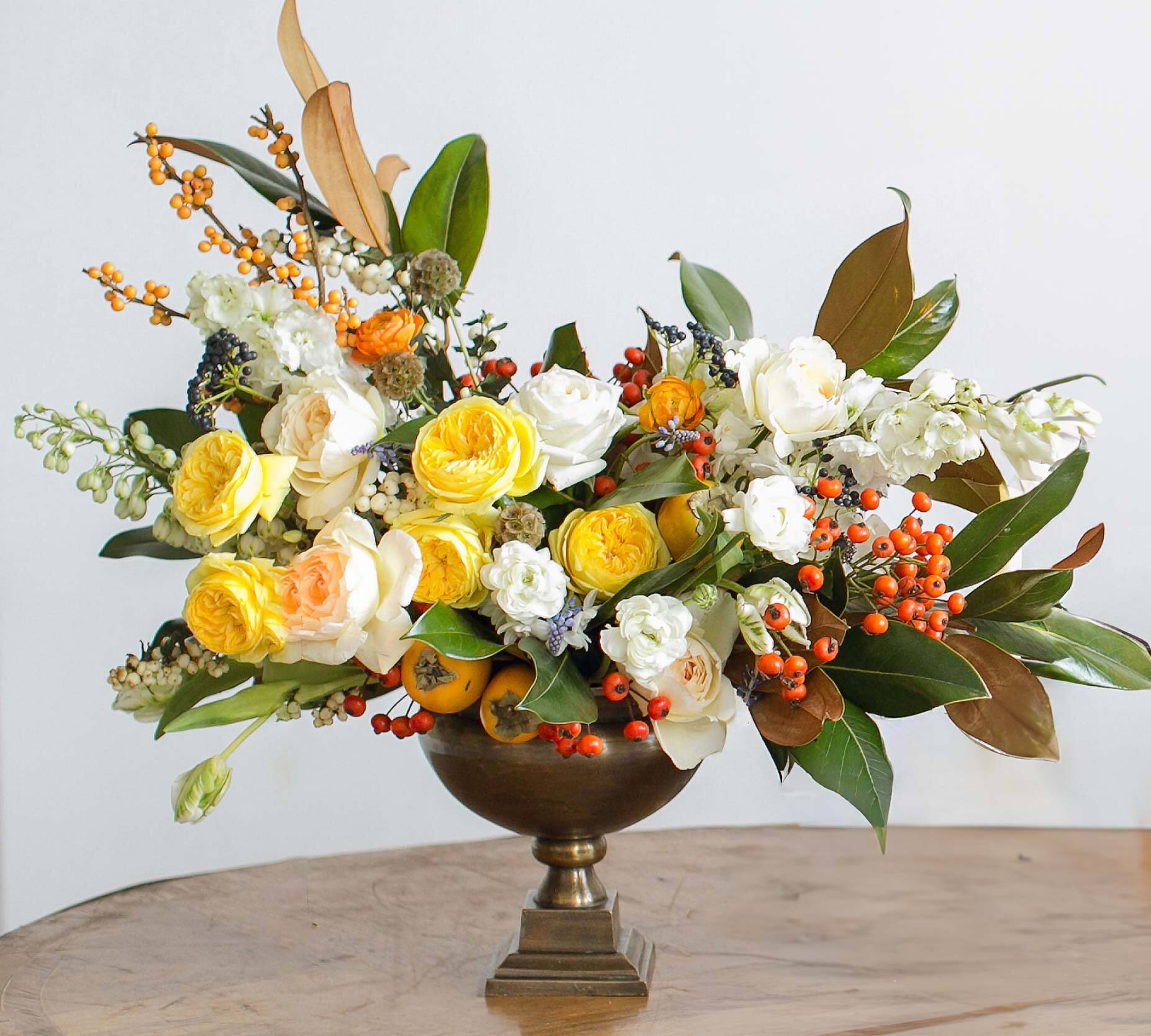 Yellow and white roses arranged in a bronze pedestal vase