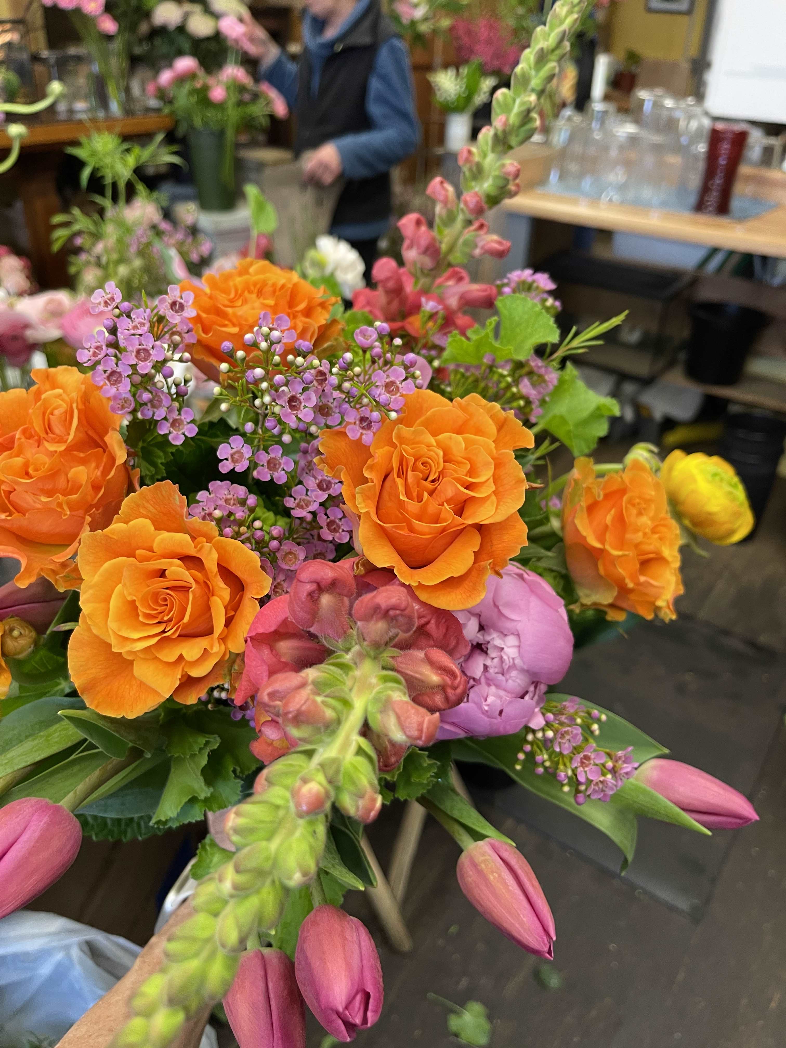 Bouquet of orange roses, pink tulips, and purple filler flowers