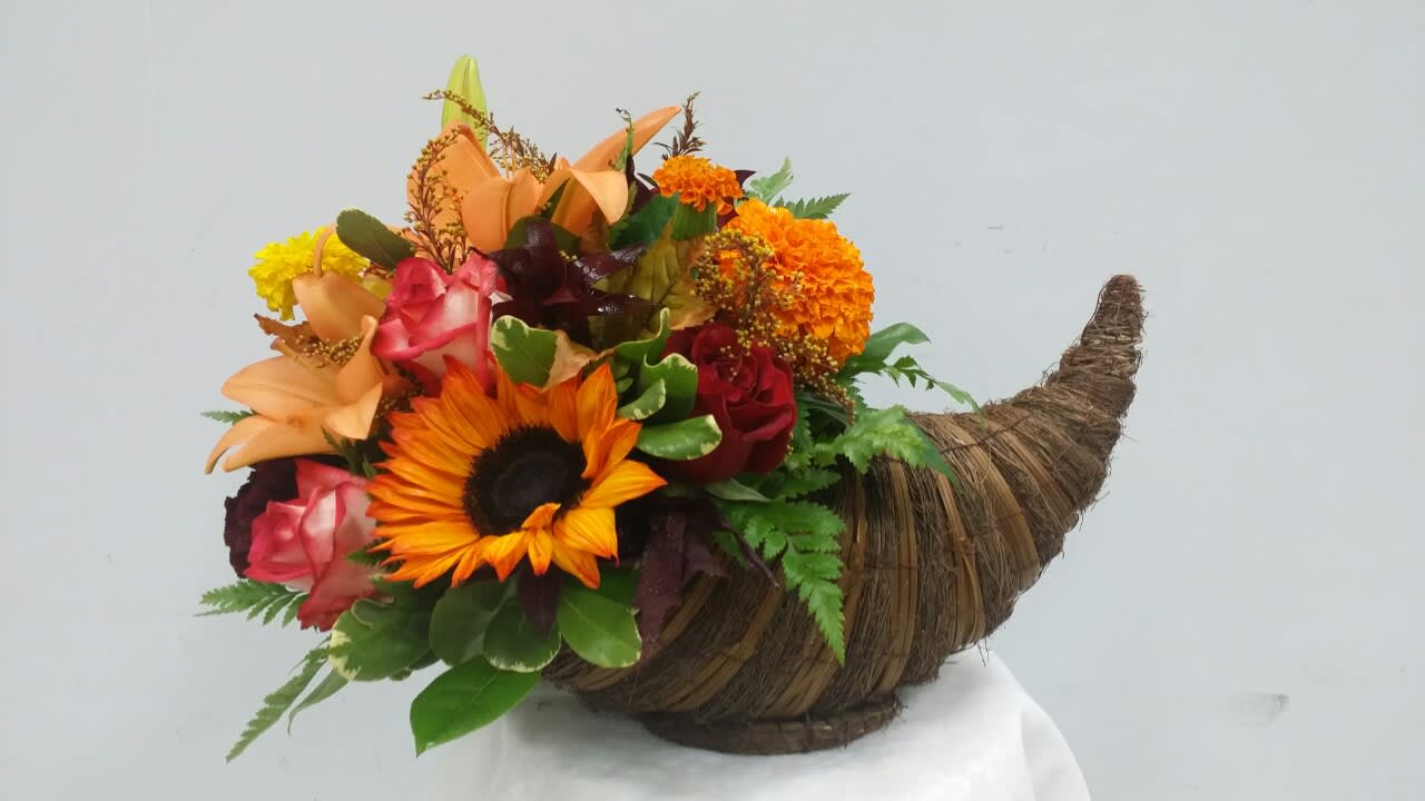 Mixed bouquet in a woven horn-shaped container with a sunflower and roses