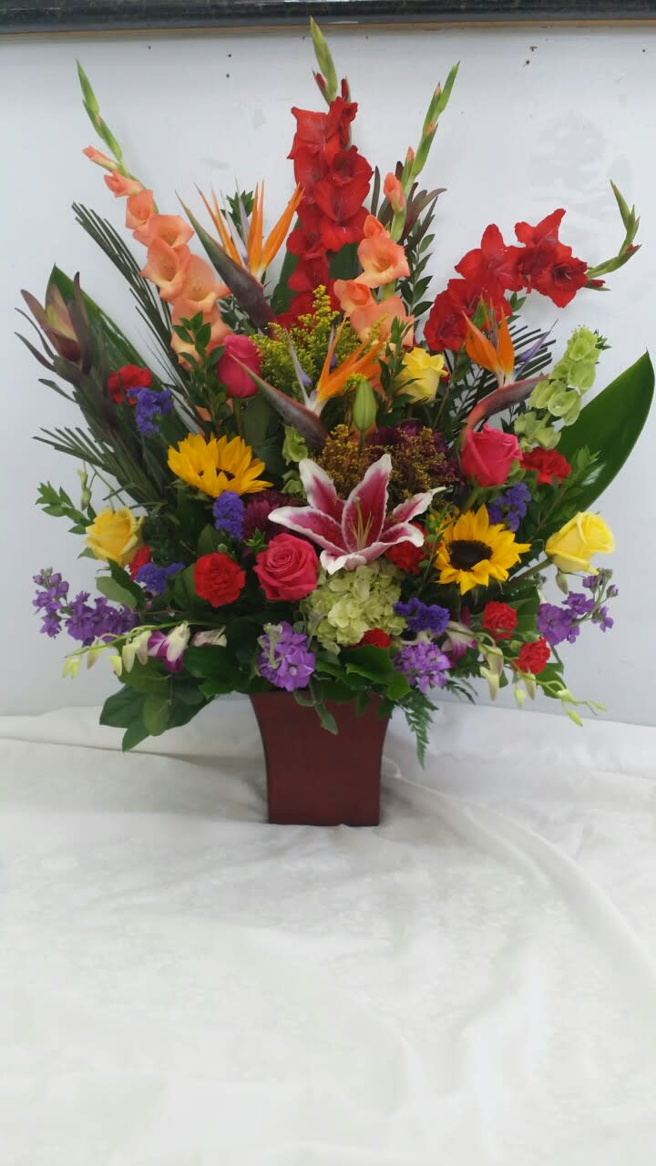 Tall mixed flower arrangement in a burgundy vase