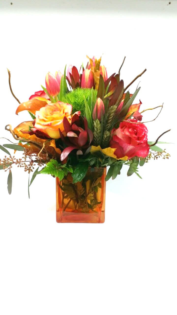 Mixed bouquet of roses and tulips in an orange glass vase