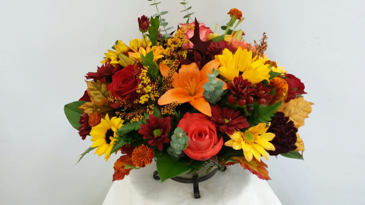 Mixed bouquet with red, yellow, and orange flowers in a low holder