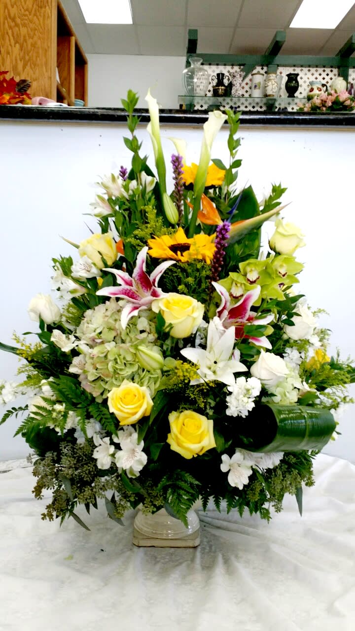 Large mixed floral arrangement with yellow roses and white lilies in a vase
