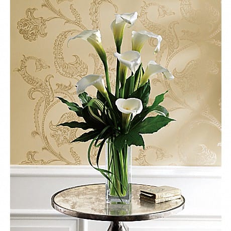 White calla lilies in a tall glass vase on a round table