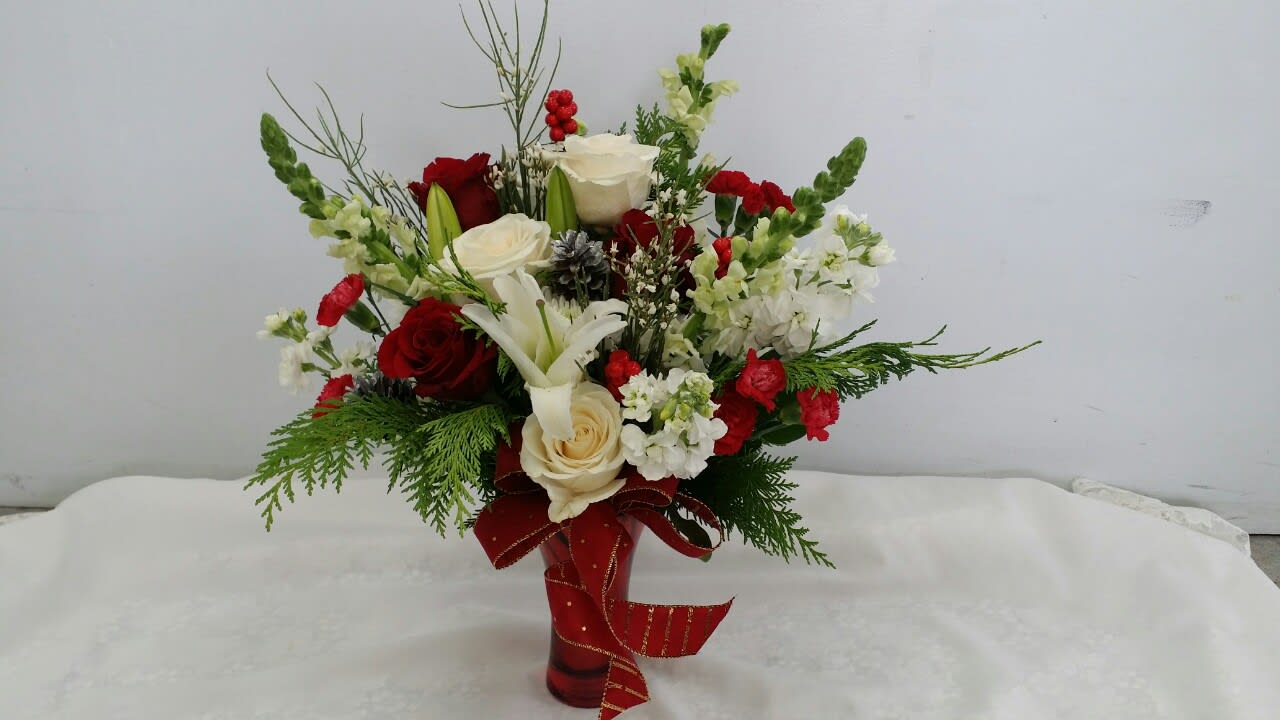 Red and white floral arrangement in a red vase with a ribbon