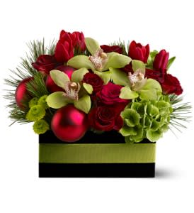 Holiday Chic - A mix of elegant blossoms such as roses, orchids and hydrangea in shades of bold red and pale green is arranged with gleaming red ornament balls in a ribbon-trimmed wooden box. A true display of holiday chic!  A mix of fresh flowers such as cymbidium orchids, roses, hydrangea and tulips – in shades of red and green – is arranged in a wooden box with red ornament balls and a green ribbon.  Approximately 12" (W) x 11" (H)  Orientation: All-Around  As Shown : TFWEB272